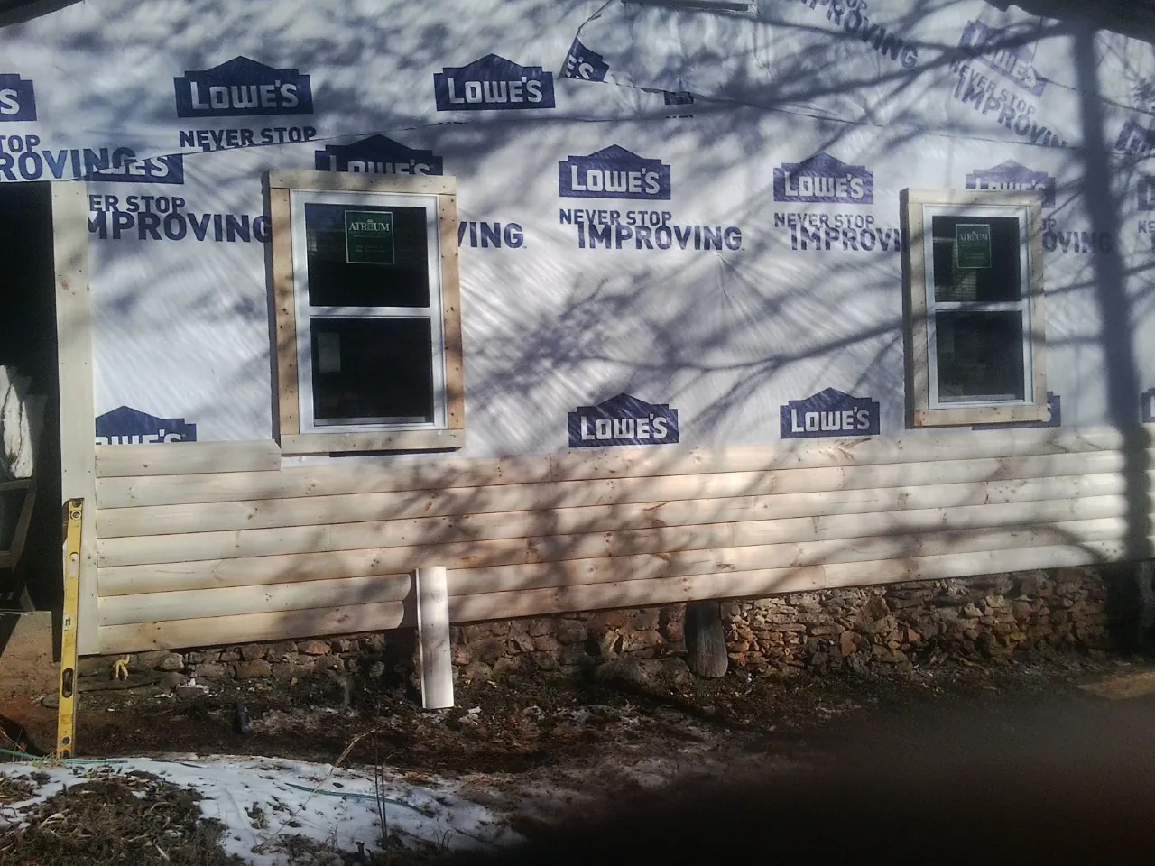 House wrap and new log siding going up on an exterior wall in La Plume