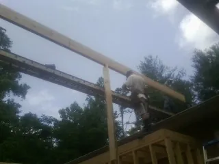 Carpenter setting a ridge beam over a new addition frame — Ice Dam Removal by Roofing Brothers in La Plume