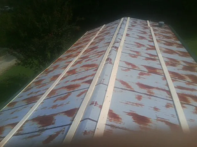 Rusted metal roof panels with new wood purlins before replacement — Storm Damage Roof Repair in La Plume by Roofing Brothers