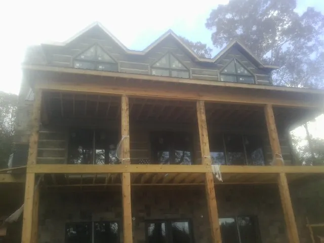 Dormers and porch framing on a large log home under construction — Roof Coating work by our crew in La Plume