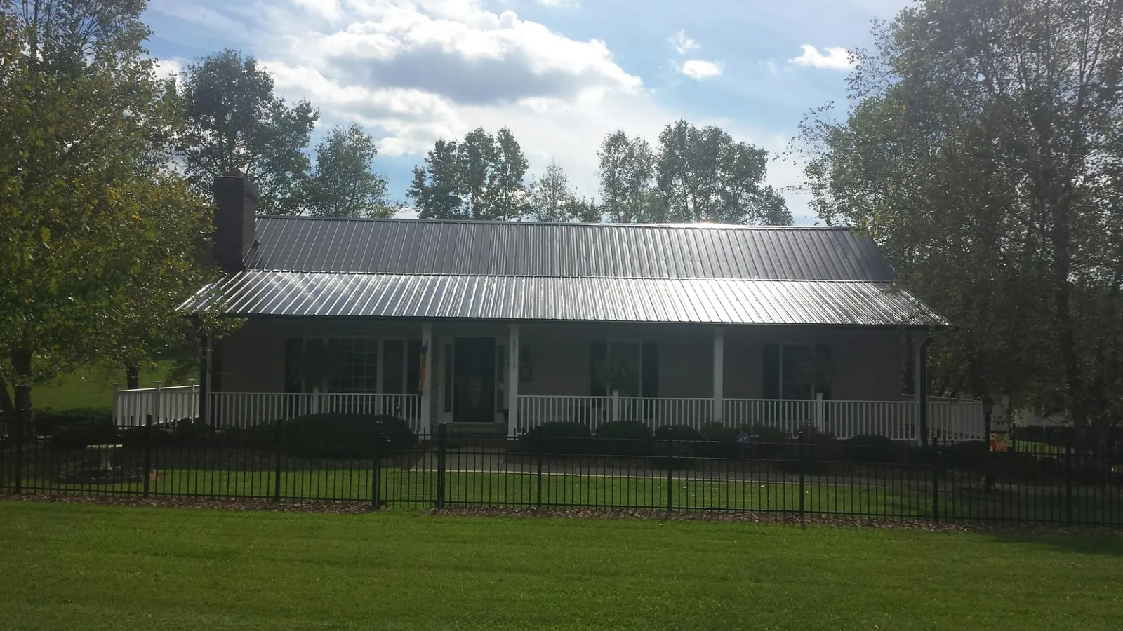 Gray metal roof on a brick ranch with a full width front porch — Gutter Guard Installation work by our crew in La Plume
