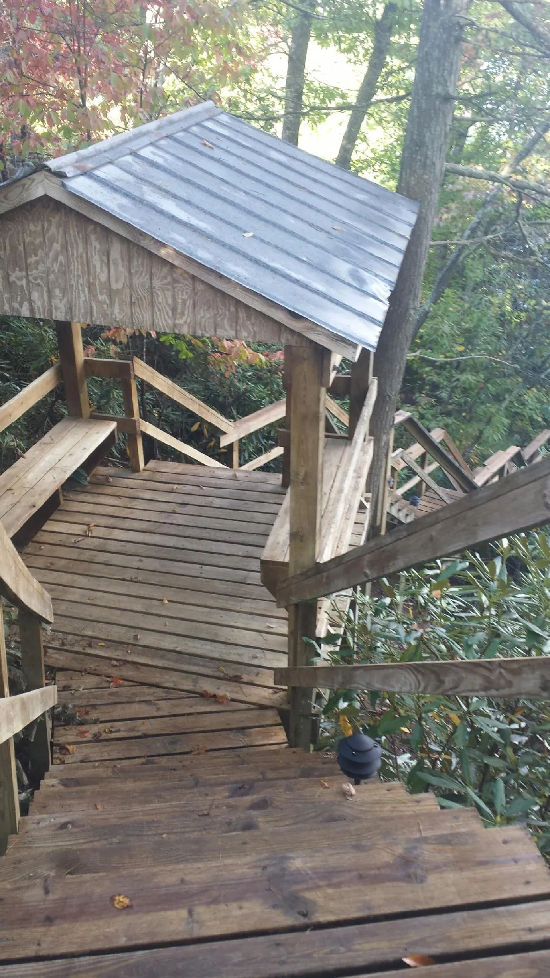 Metal roofed shelter over wooden steps on a wooded walkway — Skylight Repair & Installation work by our crew in La Plume