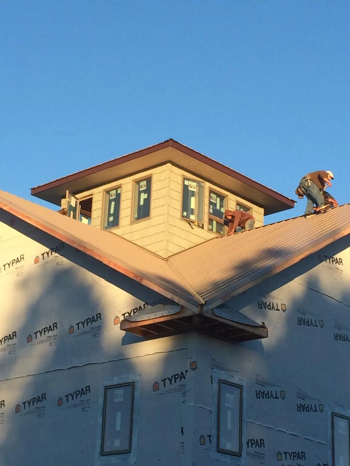 Roofers working around a rooftop cupola on a new metal roof at sunset — Roof Waterproofing in La Plume by Roofing Brothers